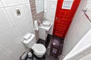 Casa de banho compacta com sanita, lavatório e porta vermelha.
