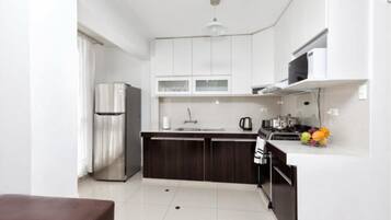 Una cocina moderna con armarios blancos, un refrigerador de acero inoxidable, un microondas y un fregadero.
