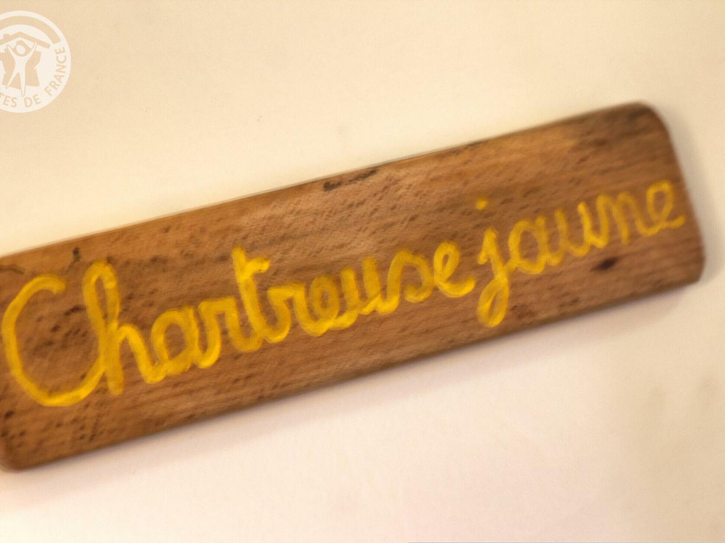 Une plaque en bois portant l’inscription « Chartrouze jaume » en lettres jaunes.