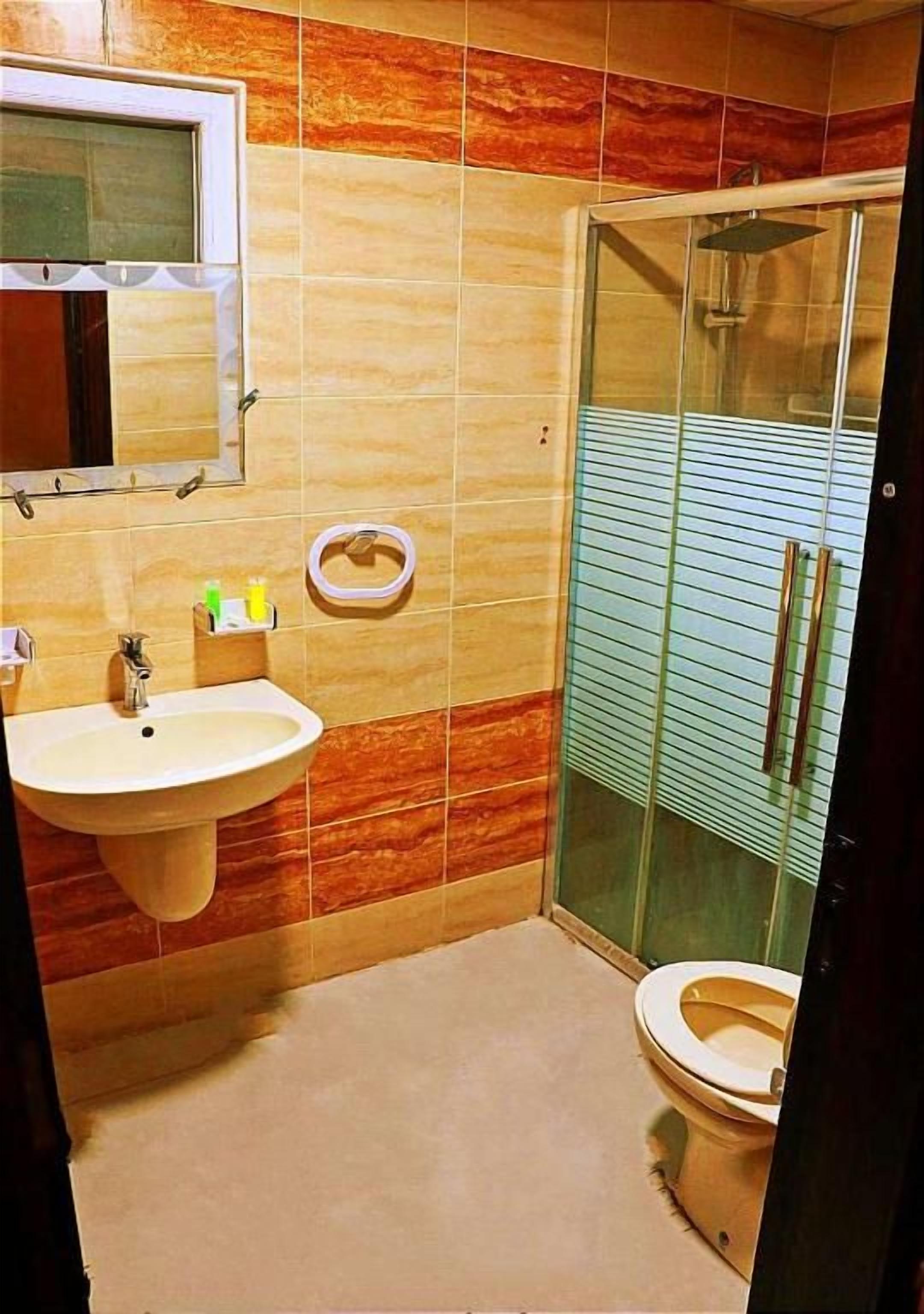 Un bagno con lavandino, WC e box doccia in vetro.