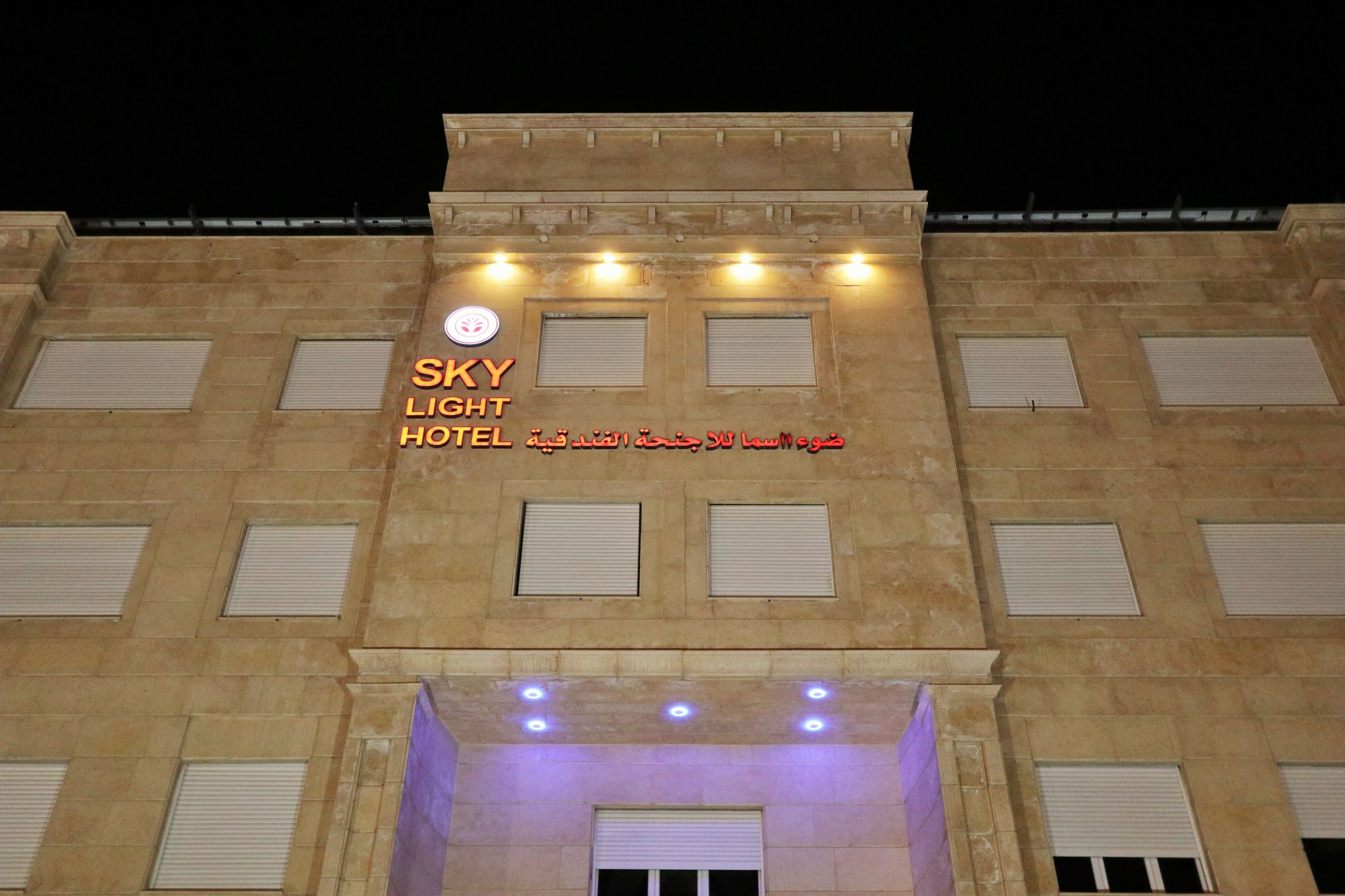 A hotel facade with the name "SKY LIGHT HOTEL" and Arabic text.