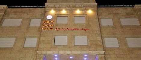A hotel facade with the name "SKY LIGHT HOTEL" and Arabic text.