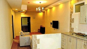 A compact living space with a kitchenette, a sofa, a dining area, and a chandelier. - Skylight Apartments (Amman)