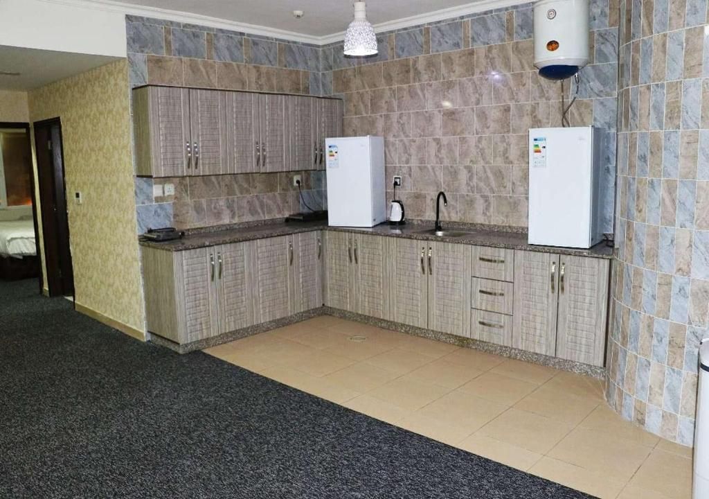 A kitchen with tiled walls, a built-in refrigerator, a sink, and a countertop.
