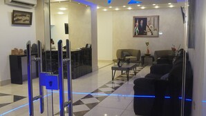 A lobby with a reception desk, seating area, and a glass partition with a keypad lock. - Skylight Apartments (Amman)