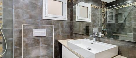 Une salle de bain moderne avec un grand miroir, une baignoire et des toilettes.