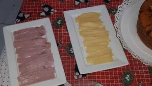 A table with food items including a plate of sliced meat, a plate of bread, and a container of rolls. - Encantos dos Sonhos (Ipojuca)