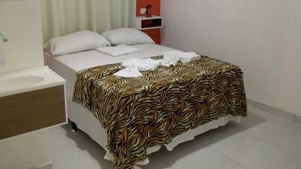 A bedroom with a bed, a nightstand, a mirror, and an air conditioning unit. - Encantos dos Sonhos (Ipojuca)