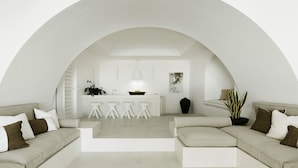 Un salon moderne avec un espace cuisine sous un plafond en arc de cercle, comprenant un canapé, une table basse et un ensemble de salle à manger.