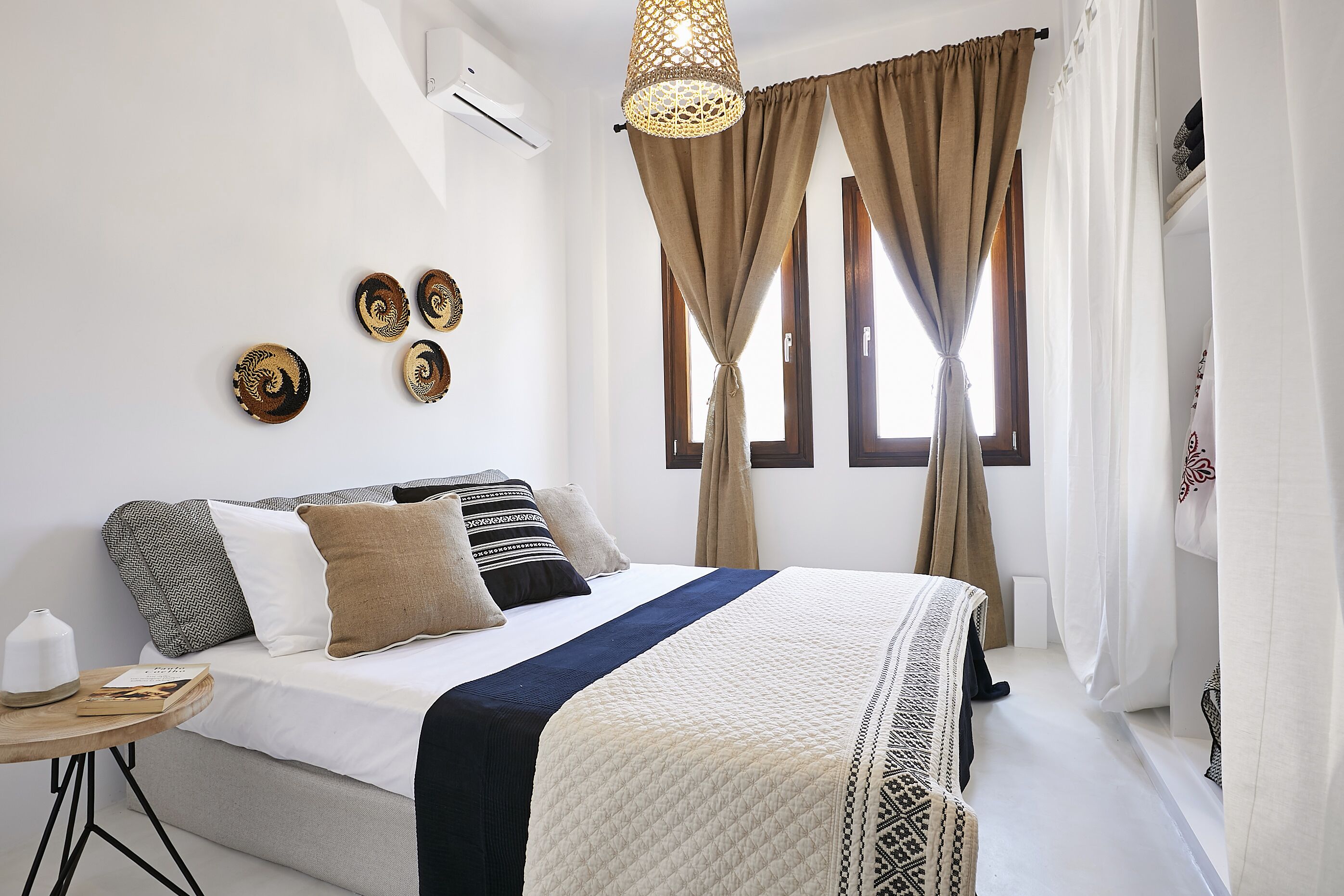A neatly arranged bedroom with a bed, bedside table, and decorative wall pieces.