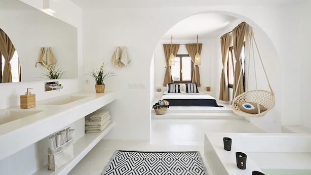 Une salle de bain moderne avec un grand miroir, un meuble-lavabo blanc et une chaise suspendue.