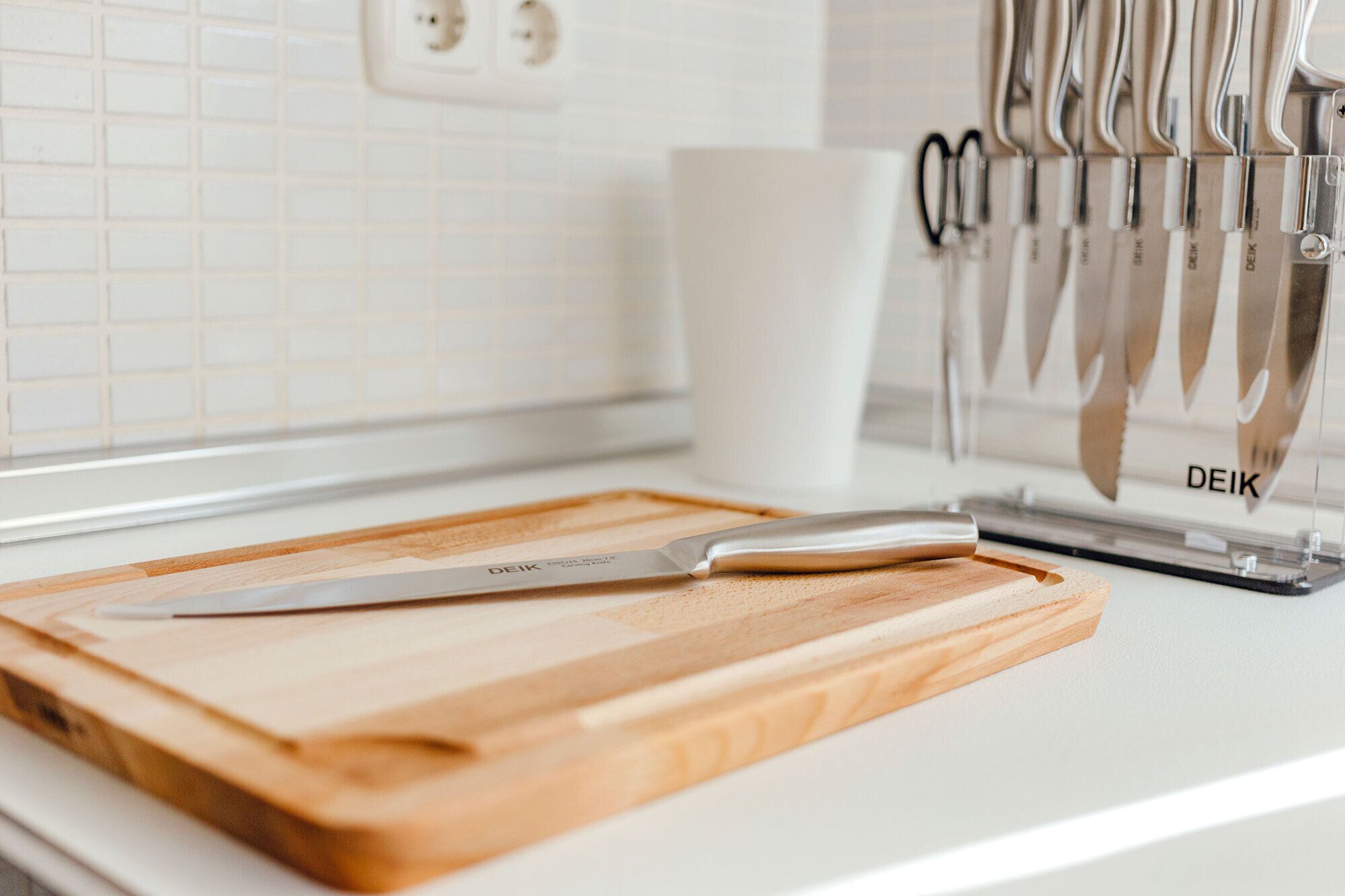 A kitchen counter with a wooden cutting board, a knife, and a knife block.