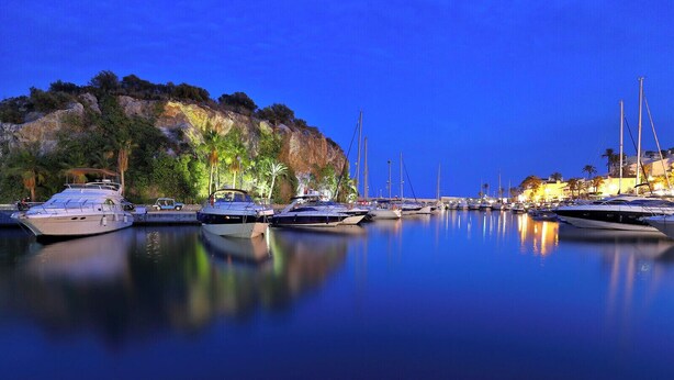A marina with boats docked at night, calm water, and a rocky cliff in the background. - Cotobro Rental House (Almuñécar)