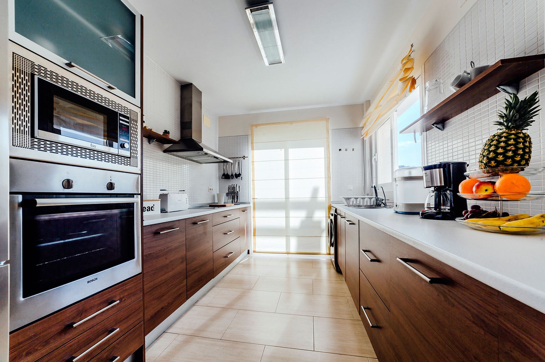 Une cuisine moderne dotée d’appareils électroménagers en acier inoxydable, de meubles en bois et d’un revêtement mural en carreaux.