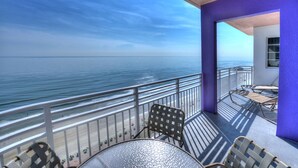 Un balcon donnant sur l’océan, aménagé avec des chaises et une table.