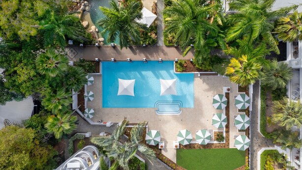 An aerial view of a resort with a central swimming pool, surrounded by palm trees and outdoor seating areas. - 74 Alamanda Palm Cove (Palm Cove)