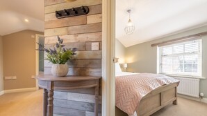 A bedroom with a wooden headboard, a bedside table with a plant, a bed with a pink quilt, and a window with blinds. - Sandpiper's Cottage, South Creake, Norfolk (South Creake)