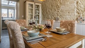 A dining area with a wooden table, chairs, and a stone wall. - Sandpiper's Cottage, South Creake, Norfolk (South Creake)