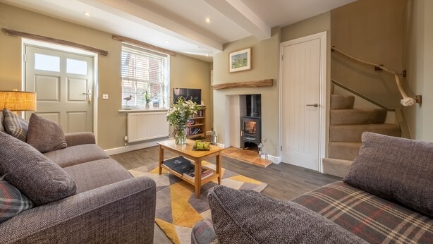 A cozy living room with a fireplace, a sofa set, and a staircase. - Sandpiper's Cottage, South Creake, Norfolk (South Creake)