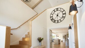 A staircase with wooden steps leading to a landing with a vase of flowers. A large wall clock is visible above the landing. - Bokes Barn, Hawkhurst , Kent (Hawkhurst, Cranbrook)