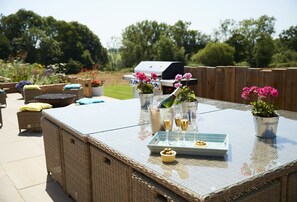 An outdoor patio with wicker furniture, a grill, and potted plants. - A contemporary barn conversion in an Area of Outstanding Natural Beauty. (Hawkhurst, Cranbrook)