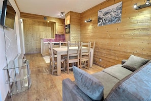 A wooden interior with a dining area, a sofa, and a kitchen.