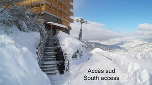 Un edificio con varios balcones y una escalera que sube una pendiente nevada.