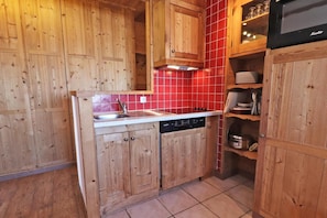 A kitchen with wooden cabinets, a red tiled backsplash, and a built-in dishwasher.