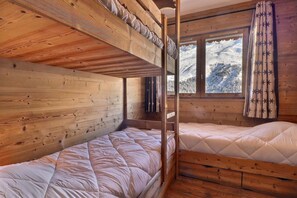 Ein Holzhütten-Zimmer mit Stockbetten und einem Fenster mit Blick auf eine verschneite Landschaft.