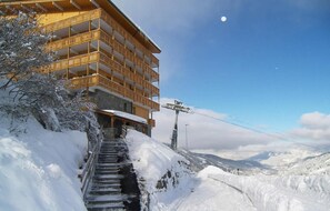 A building with multiple balconies and a staircase leading up a snowy slope.