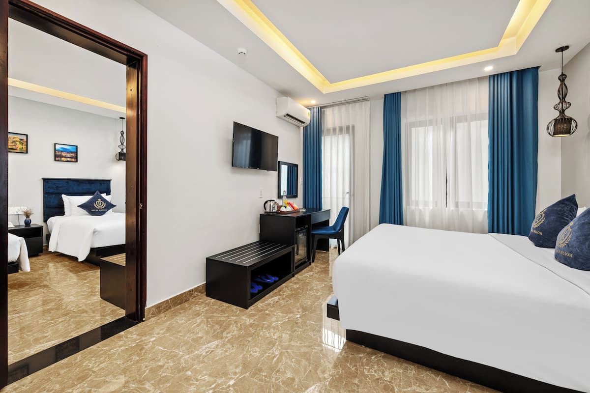 A modern hotel room with a large bed, a desk, a television, and a mirror.