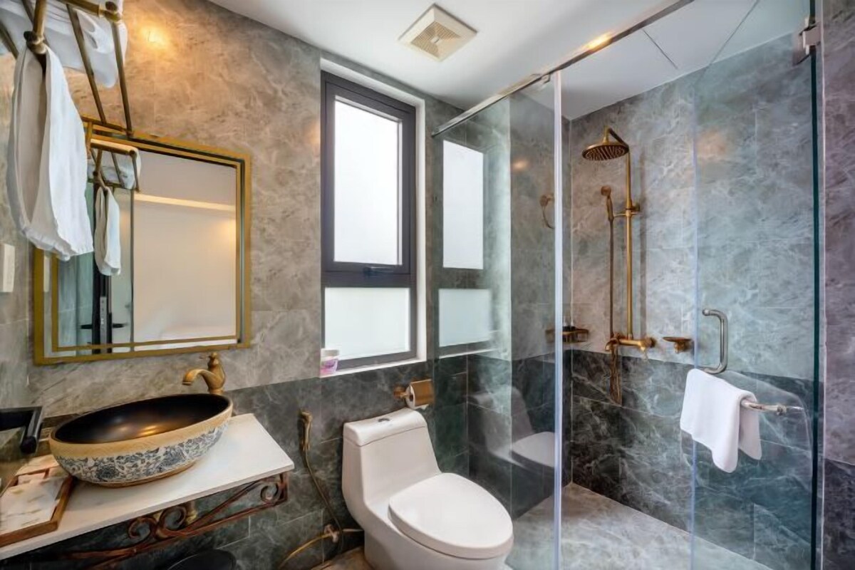A bathroom with a large vessel sink, a toilet, and a glass-enclosed shower area.