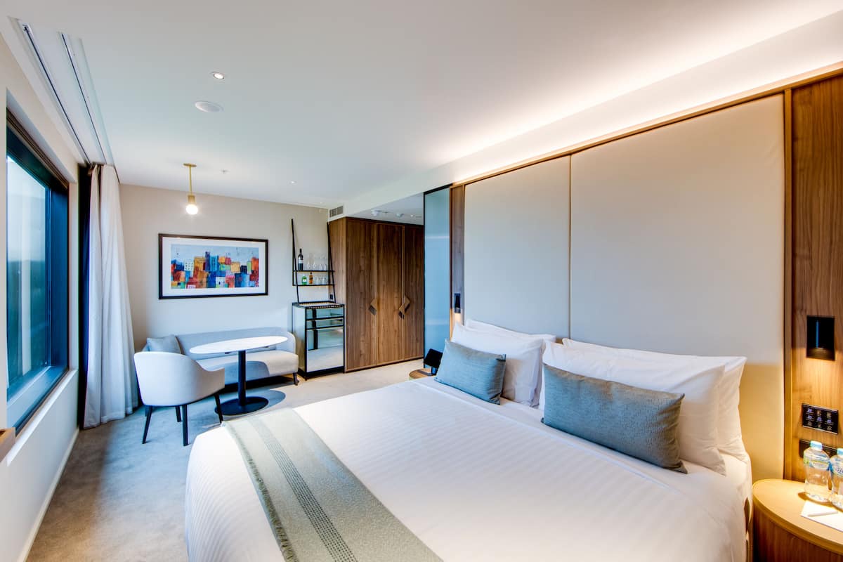 Une chambre d’hôtel moderne dotée d’un grand lit, d’un bureau et d’un coin salon.