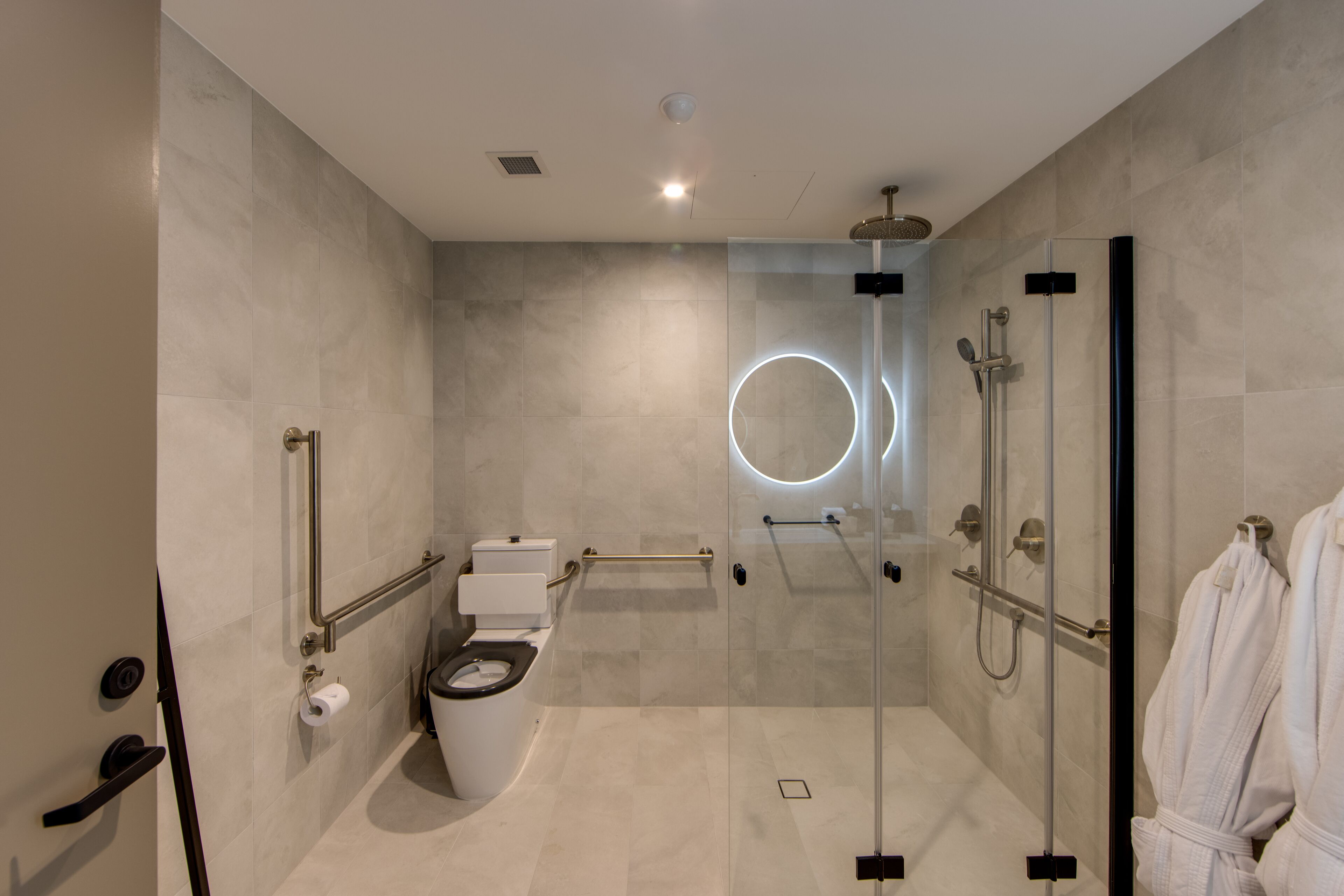 A modern bathroom with a toilet, bidet, and glass-enclosed shower area.