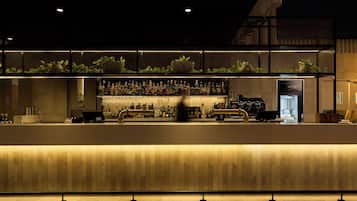 A bar area with a counter, shelves of bottles, and a cash register.