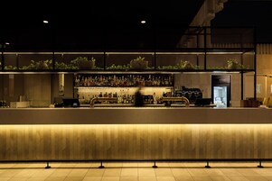 Un espace bar avec un comptoir, des étagères remplies de bouteilles et une caisse enregistreuse.