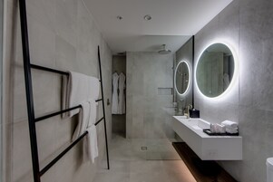 Un baño moderno con cabina de ducha de vidrio, tocador con espejo y perchero para toallas.