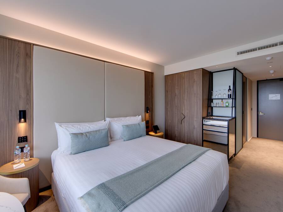 Een hotelkamer met een groot bed, nachtkastjes, een kledingkast en een minibar.