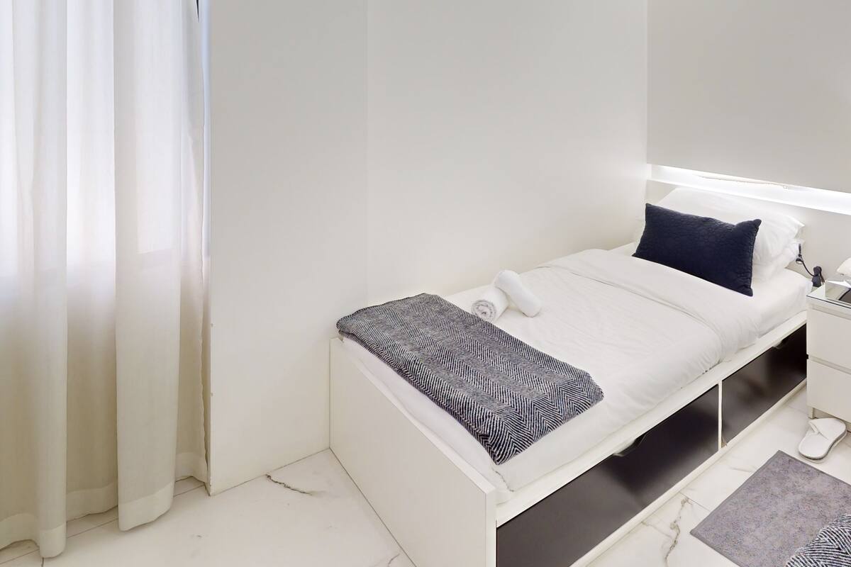 Un dormitorio moderno con cama, mesita de noche y velador.
