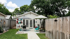 A backyard with a patio area, a wooden fence, and a house with a garage.
