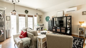 A living room with a sofa, a coffee table, a TV stand, and a chandelier.