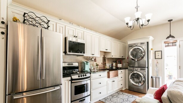 A modern kitchen with stainless steel appliances, white cabinetry, and a built-in oven.