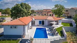 Una propiedad residencial con piscina, terraza cubierta y jardín.