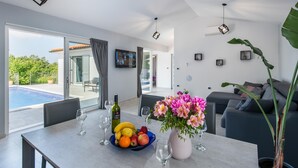 Una sala de estar moderna con comedor, un ventanal y vistas a la piscina.