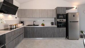Una cocina moderna con armarios grises, un refrigerador de acero inoxidable, horno integrado y un microondas.