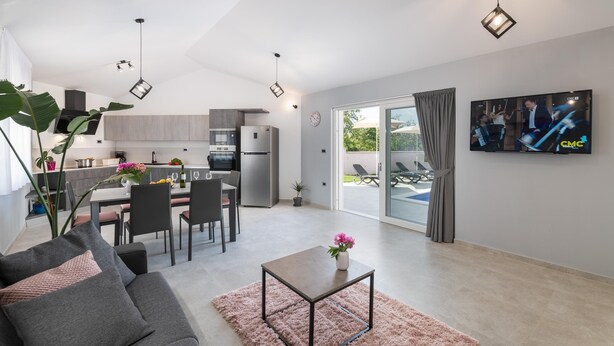 Un espacio habitable moderno con cocina, comedor y televisor montado en la pared.