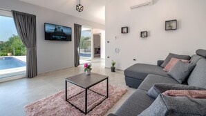 Una sala de estar moderna con un sofá gris, una mesa de centro y un televisor montado en la pared.