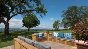 A wooden deck with built-in seating, a large tree, and a view of the countryside. - Broad  Meadows (12), Bayton , Worcestershire (Kidderminster)