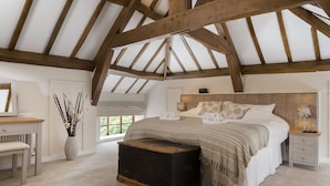 A bedroom with a wooden ceiling, a bed with a patterned pillow, a bedside table with a lamp, and a large window. - Broad  Meadows (12), Bayton , Worcestershire (Kidderminster)