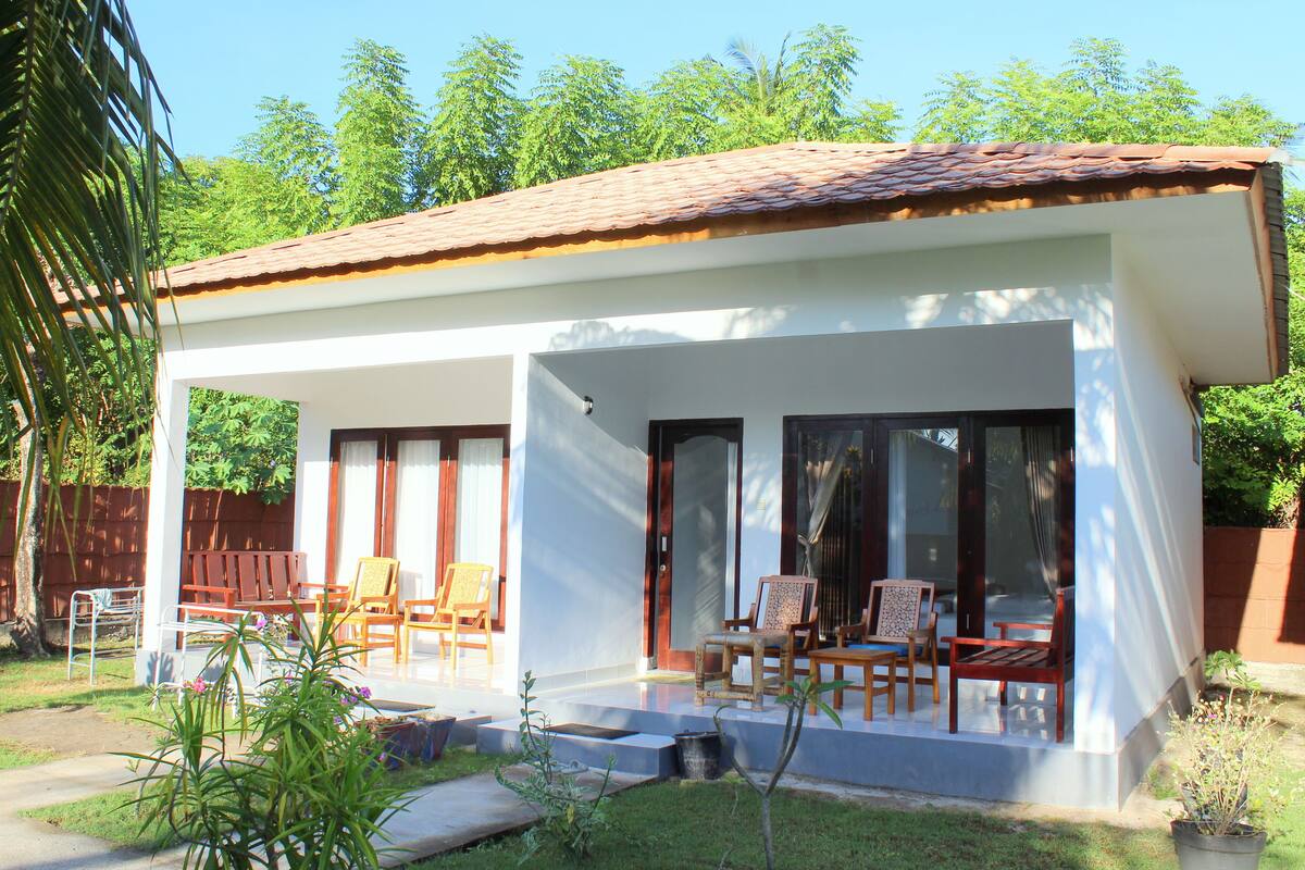 Ein modernes Haus mit überdachter Terrasse, mehreren Sitzbereichen und einem Garten.
